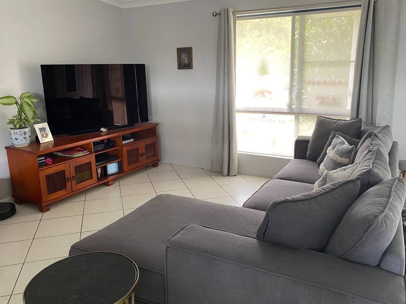 Lounge room with large flat screen smart tv, new comfy couch, aircon and fan.