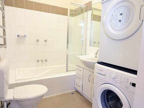 Modern bathroom with towel warmer includes washing and drying machines